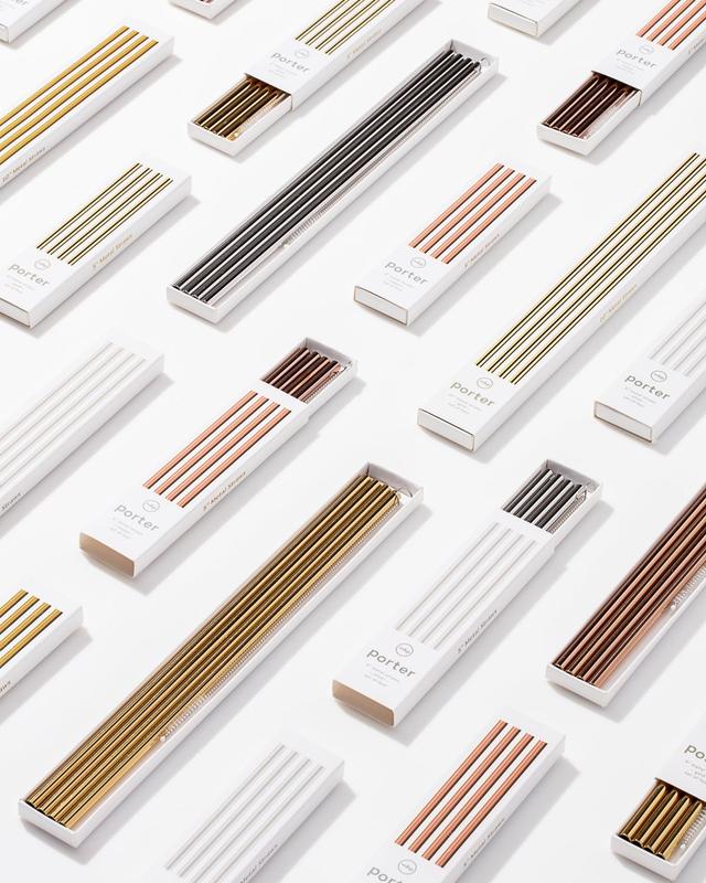 multiple boxes of reusable sustainable metal straws gold silver copper laid across white counter