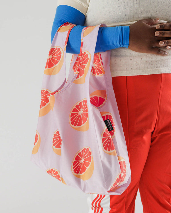 woman carrying reusable bag in grapefruit pattern over forarm 