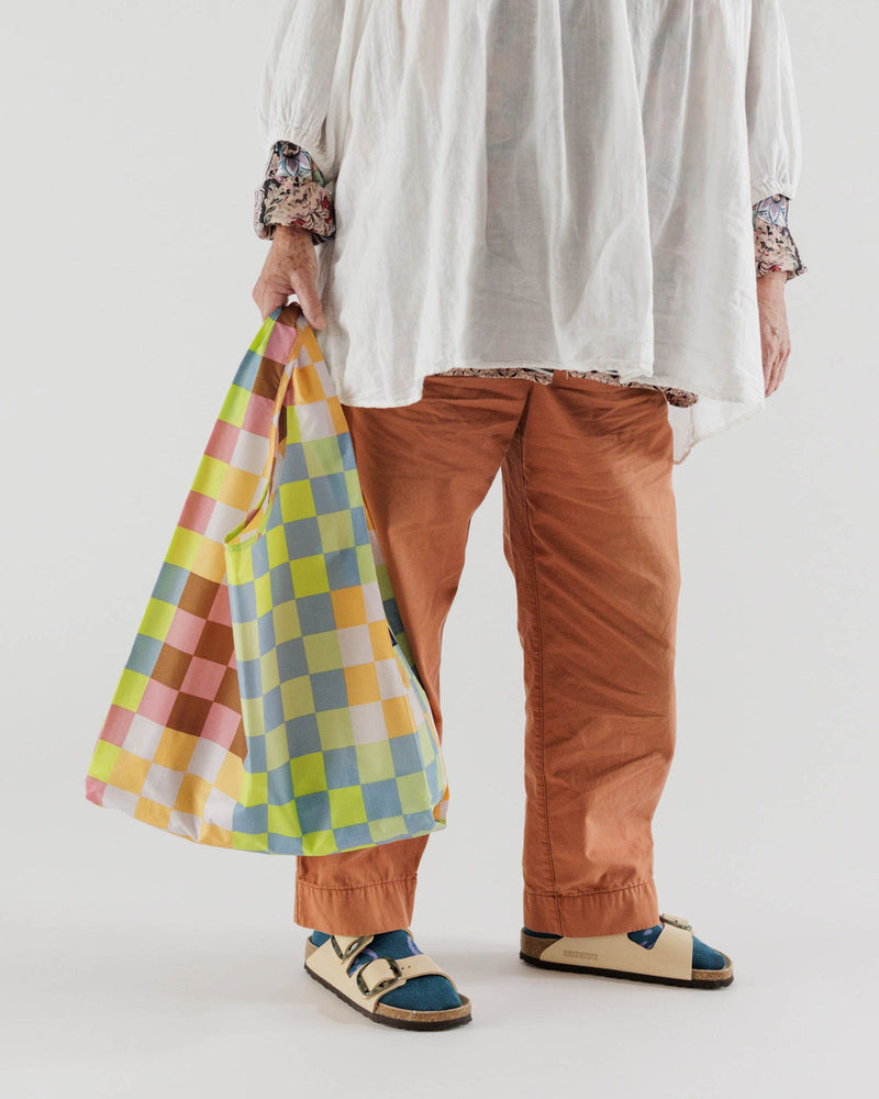 person carry reusbale baggu bag in hand with check pattern