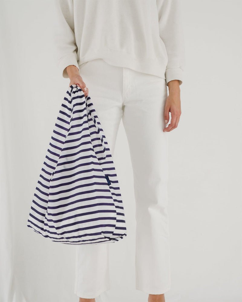 woman holding in hand baggu standard bag in white and navy striped pattern