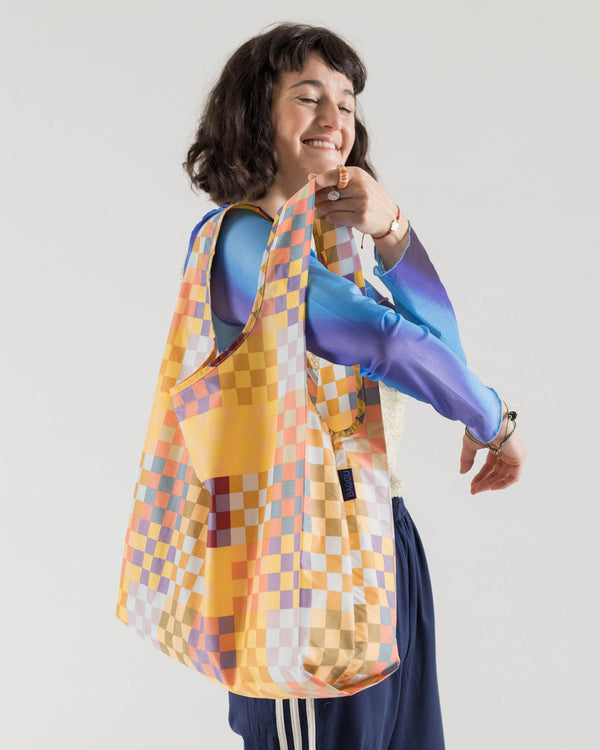 woman putting baggu reusable bag over shoulder in medium checkered pattern 