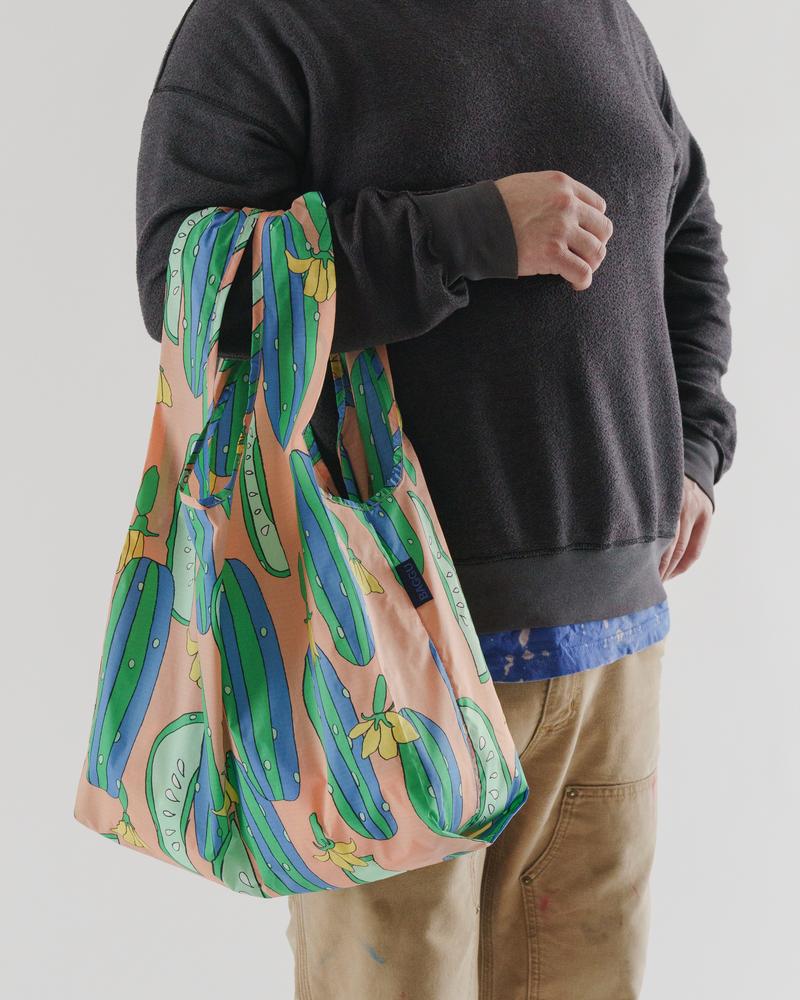 man carrying baggu cucumber reusable bag in arm