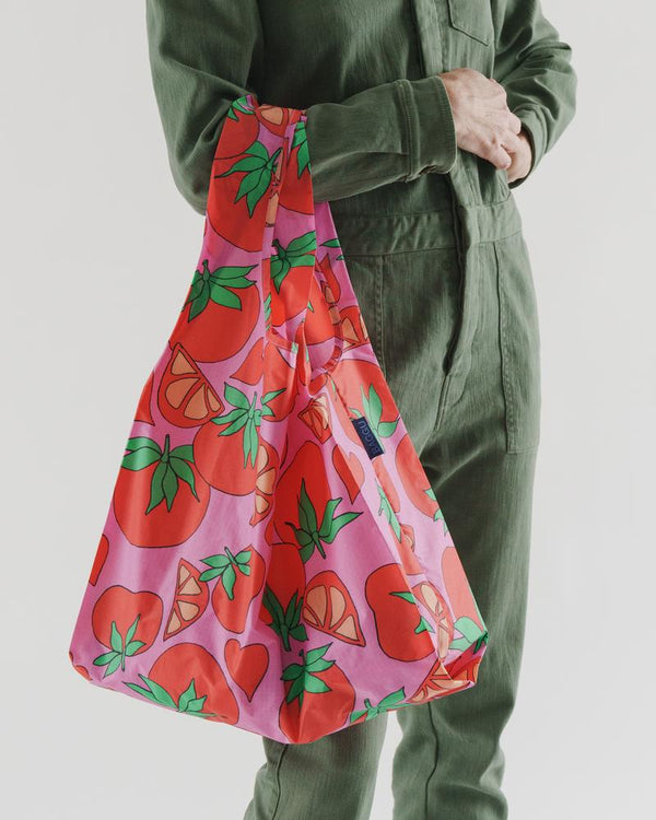 woman carrying on arm baggu reusable bag tomatoes