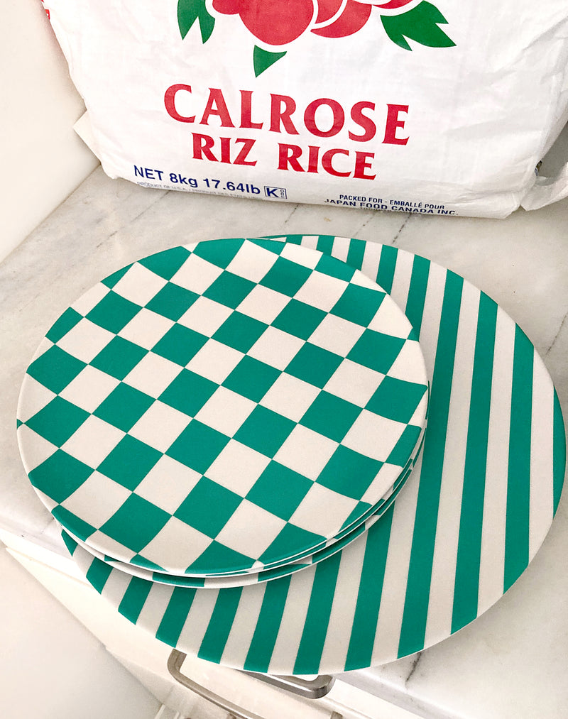 bamboo side plate in green and white checkers stacked on green and white striped dinner plates next to large bag of rice