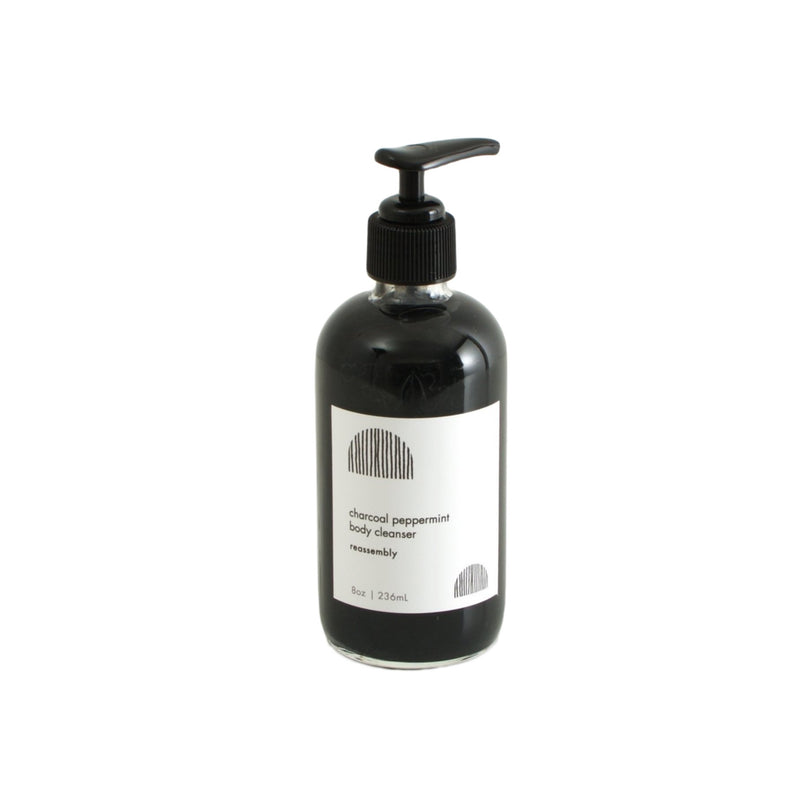 reassembly botanical charcoal peppermint black liquid body cleanser in pump glass bottle over white background