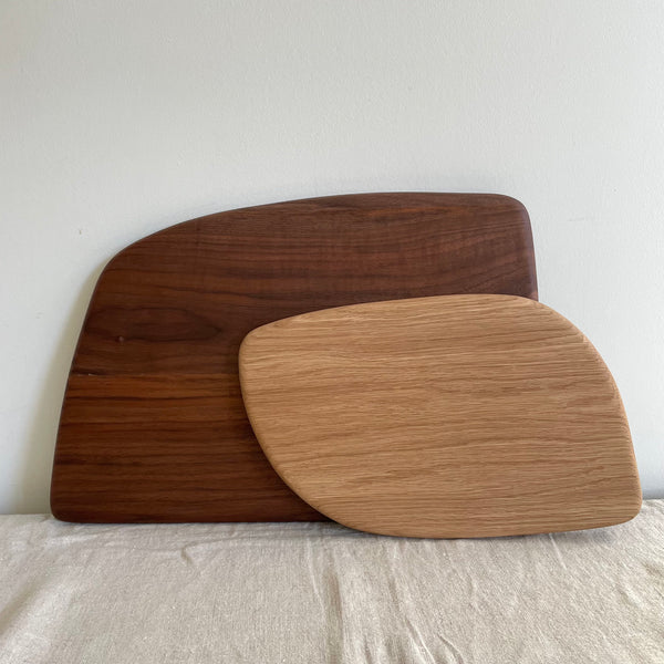 large walnut serving board behind a small white oak serving board on a linen cloth