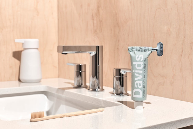 davids natural toothpaste tub with metal key twisting it down on bathroom sink