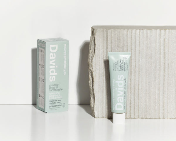 davids natural peppermint travel toothpaste box and tube upright next to grey stone