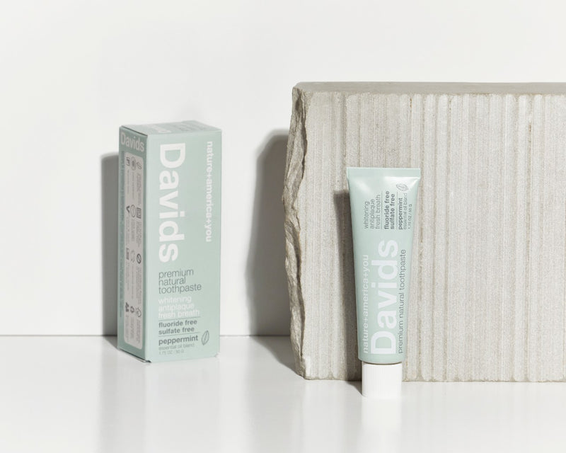 davids natural peppermint travel toothpaste box and tube upright next to grey stone