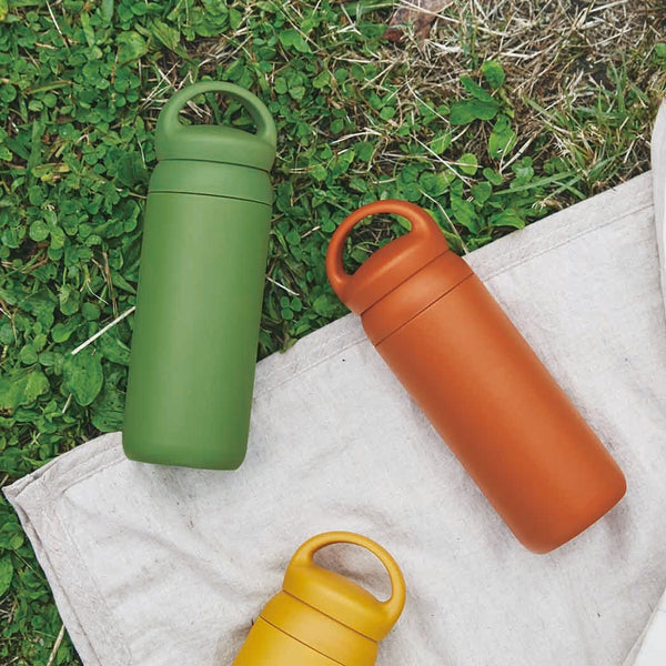 green yellow and orange kinto water bottles on grass