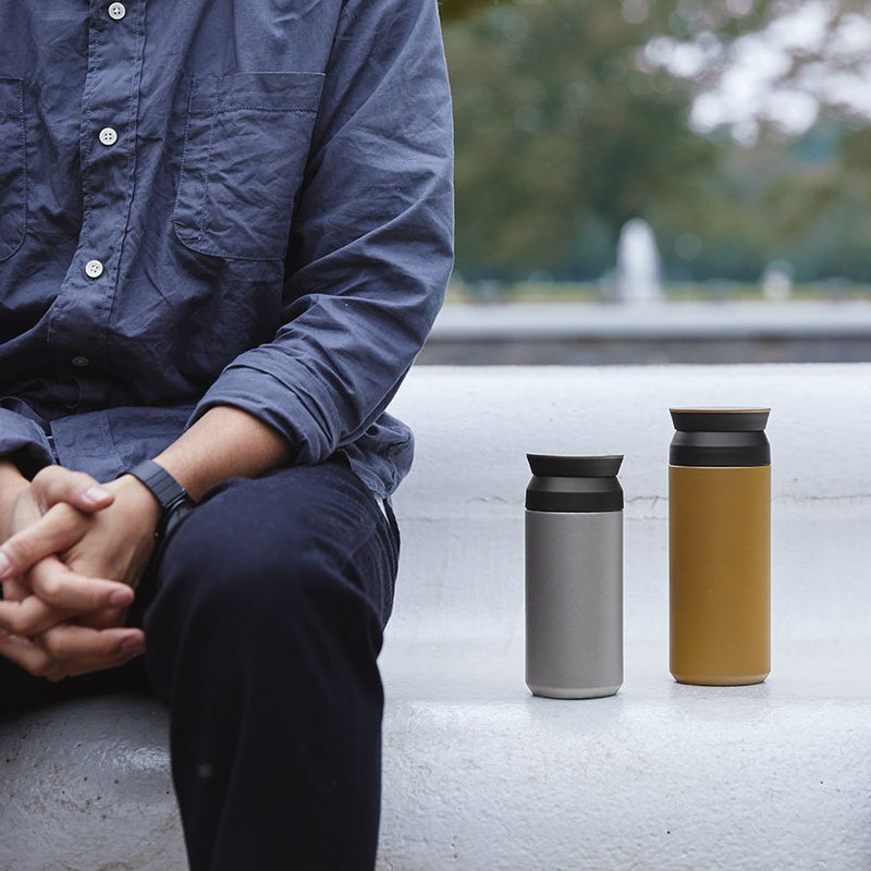 man sitting outside next to kinto travel tumblers 350ml and 500ml size