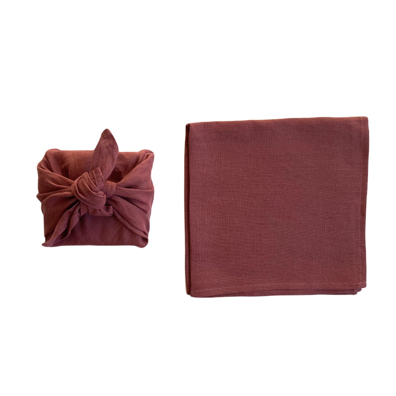 plum coloured linen furoshiki wrapped gift next to piece of linen