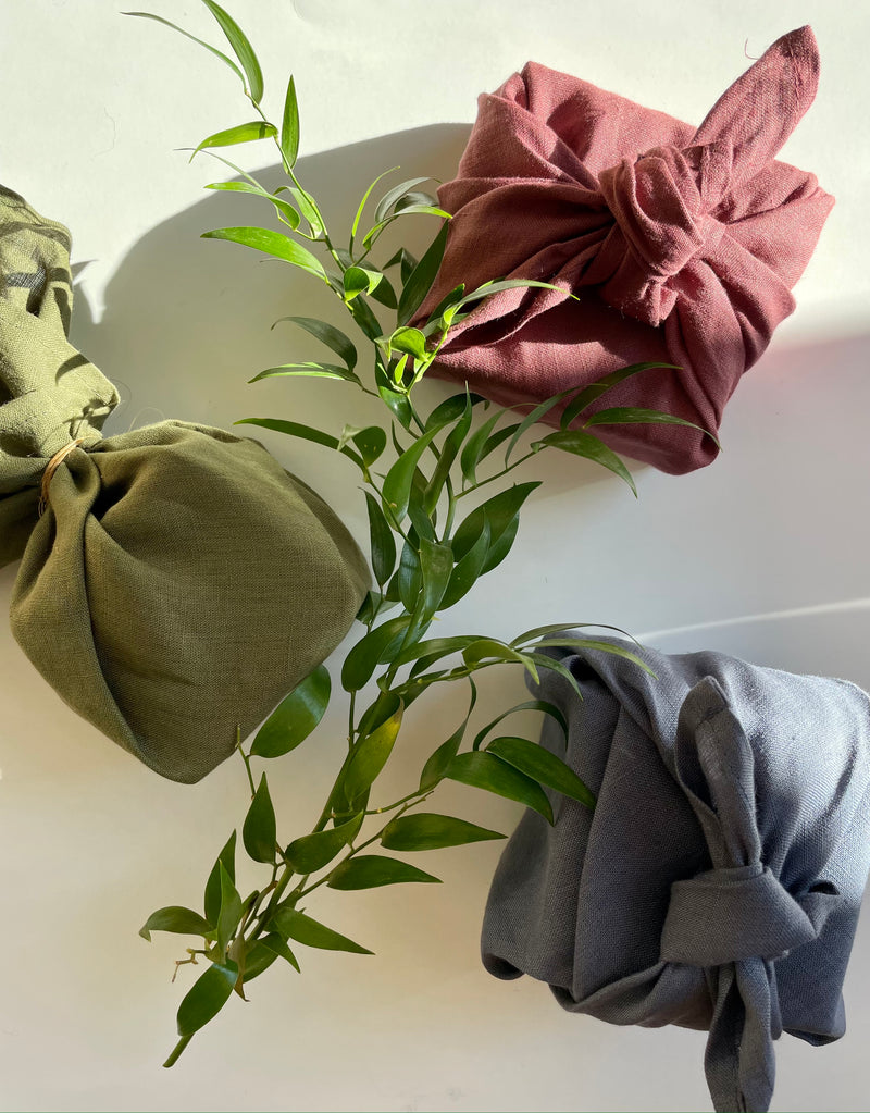 three gifts wrapped in moss, stone and plum furoshiki wraps 