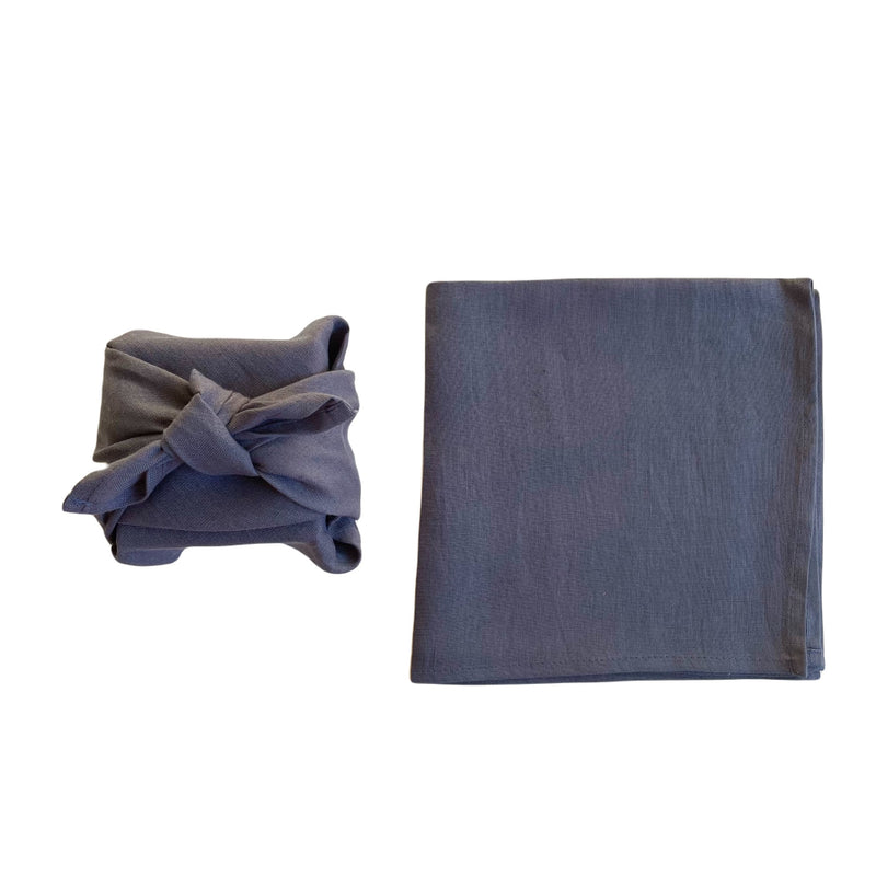 stone coloured linen furoshiki wrapped gift next to flat piece of linen