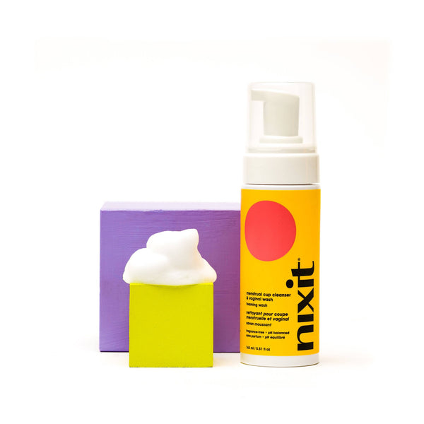 nixit foaming meantrual cup cleanser bottle and foam on yellow and purple box