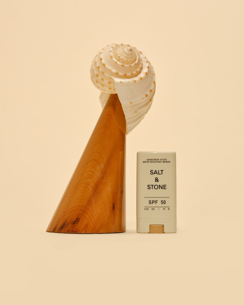 salt and stone spf 50 tinted sunscreen face stick next to seashell and wodden cone
