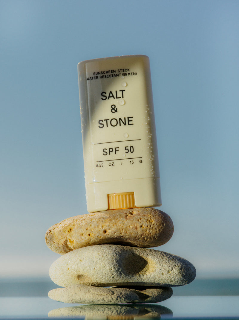 salt and stone spf 50 sunscreen stick against sky background placed on 3 rocks