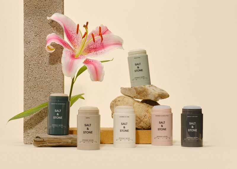 salt and stone all natural deodorant scents lined up with stones in the background and a calla lily