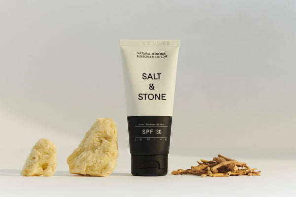 salt and stone natural spf 30 sunscreen lotion placed next to pieces of shea butter and ashwagabdha
