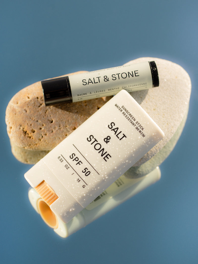 salt and stone spf 50 sunscreen face stick and spf 30 lip balm laid across two rocks