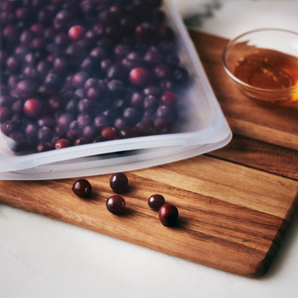 stasher reusable half gallon bag with berries inside on cutting board