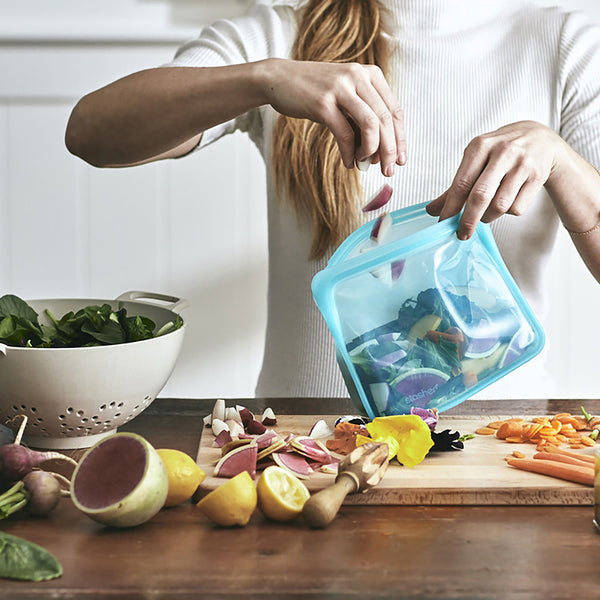 woman putting cut vegetables into stasher stand up bag