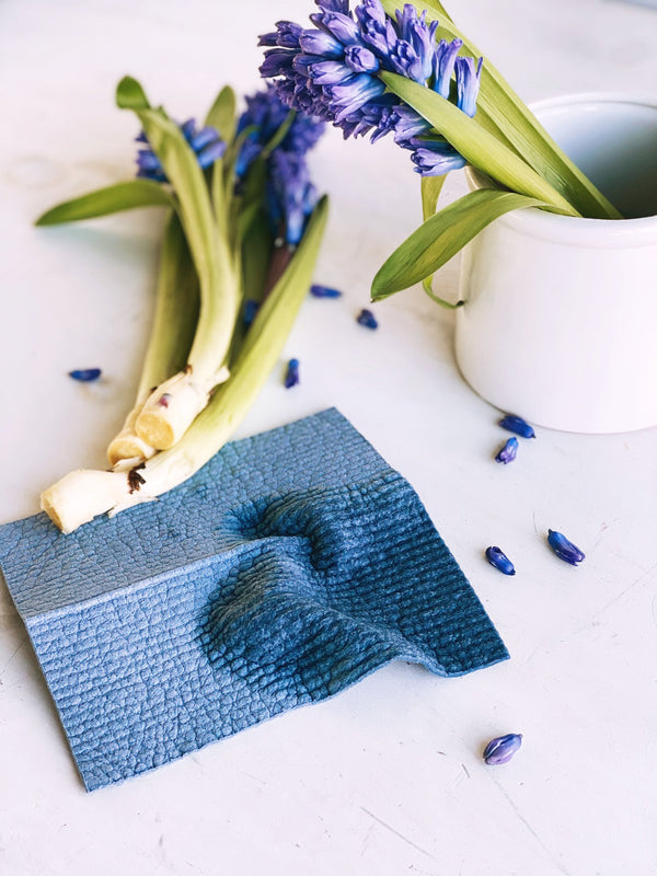 ten and co compostable sponge cloth in stone blue wet on counter next to flowers and vase