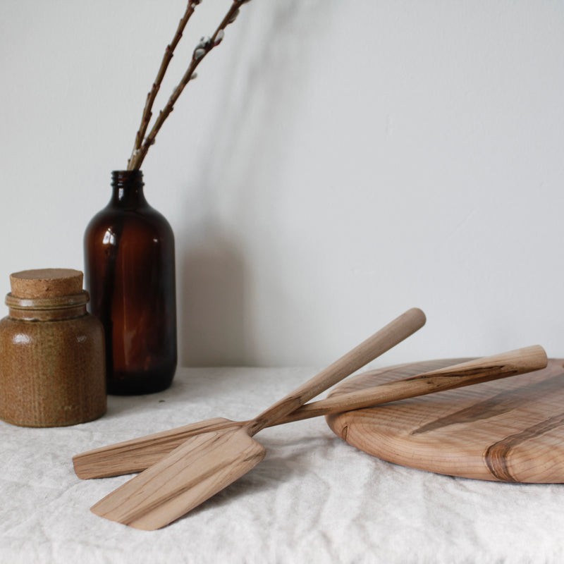 the woodsmans daughter handmade maple and walnut spatulas laying across table on cutting board